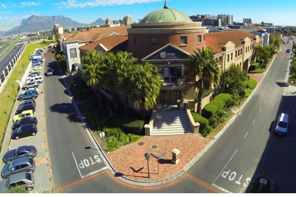 Aerial view of a commercial office building featuring a distinctive domed roof, brick facade, and landscaped entrance area with surrounding parking.