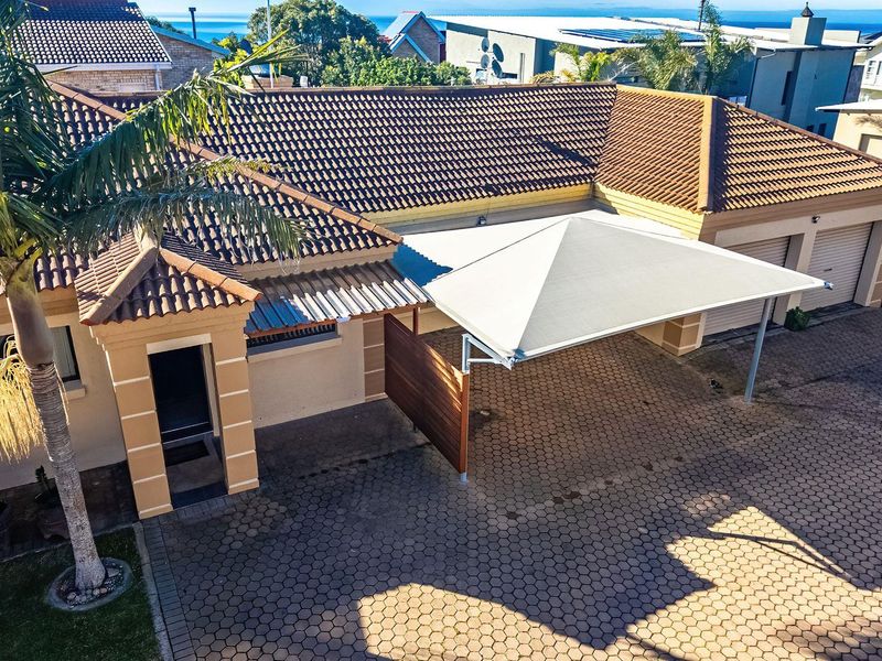 Aerial view of the townhouse front exterior featuring a paved driveway, double garage, and a modern shade sail carport structure.
