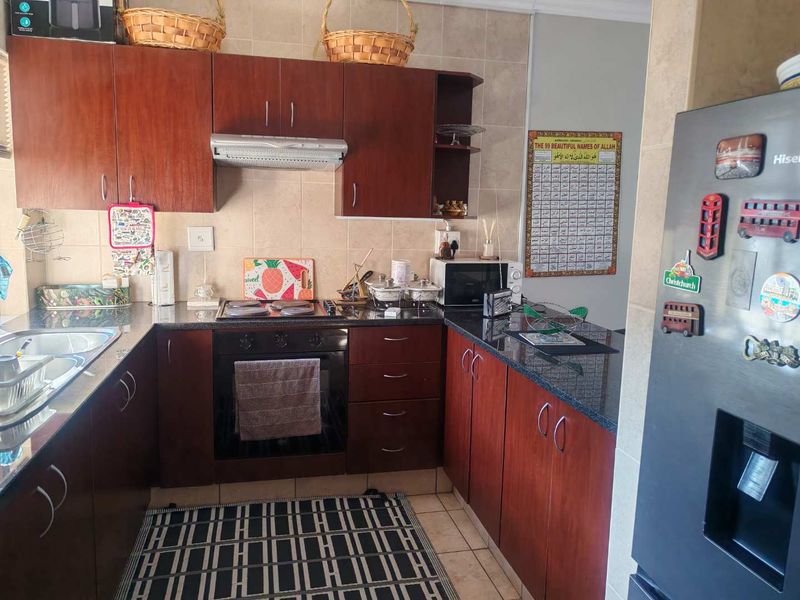 A functional kitchen featuring dark wood cabinetry, granite countertops, a built-in oven with hob, and a tiled backsplash.