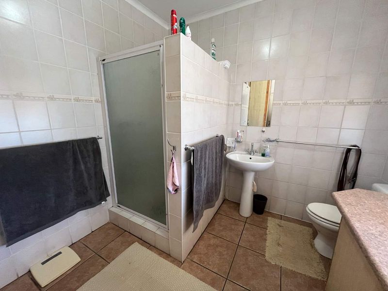 A functional bathroom featuring a pedestal basin, toilet, and a separate shower enclosure with tiled walls and flooring.