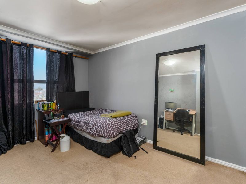 A bedroom featuring carpeted flooring, a built-in wardrobe, and cove cornicing, offering a functional space with potential for cosmetic updates.