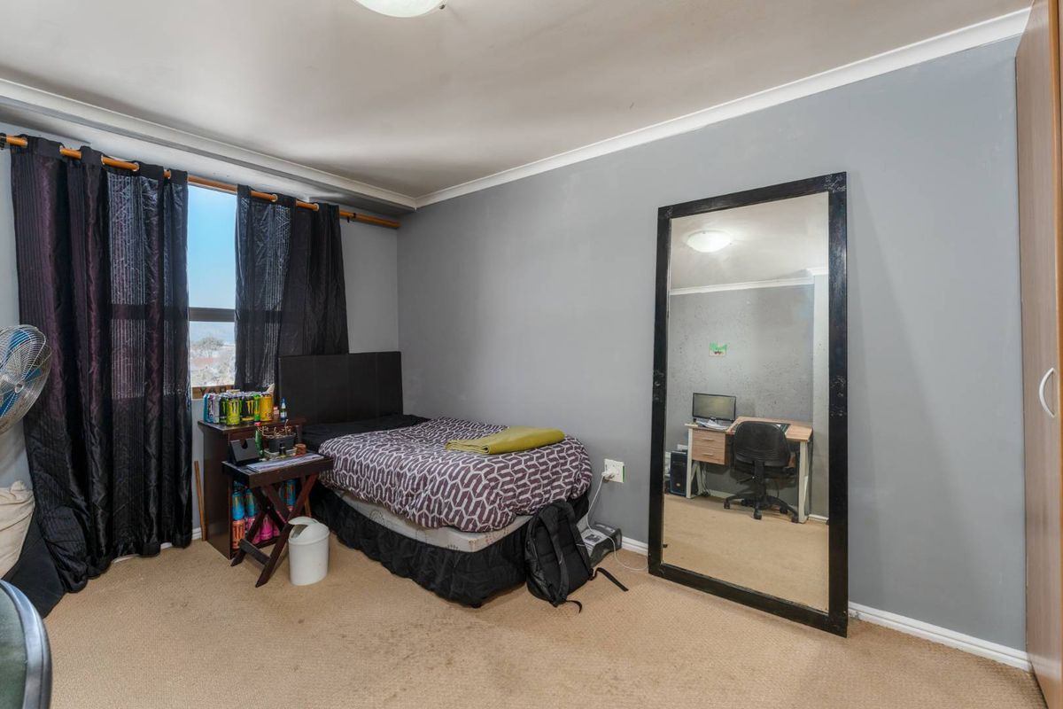 A bedroom featuring carpeted flooring, a built-in wardrobe, and cove cornicing, offering a functional space with potential for cosmetic updates.