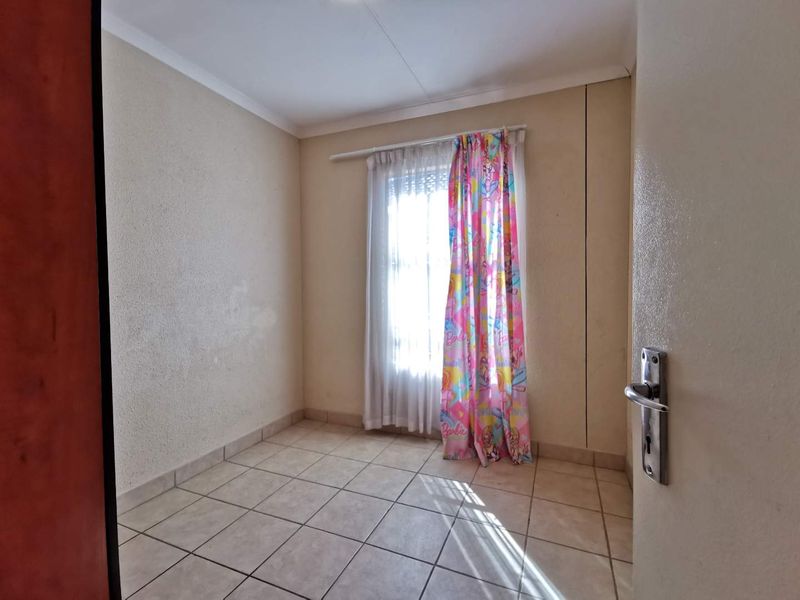 A vacant bedroom featuring tiled flooring and a window with a curtain rod, requiring minor cosmetic updates to the wall surfaces.