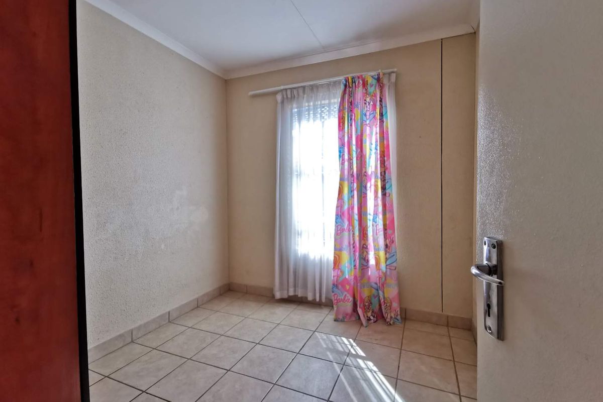 A vacant bedroom featuring tiled flooring and a window with a curtain rod, requiring minor cosmetic updates to the wall surfaces.