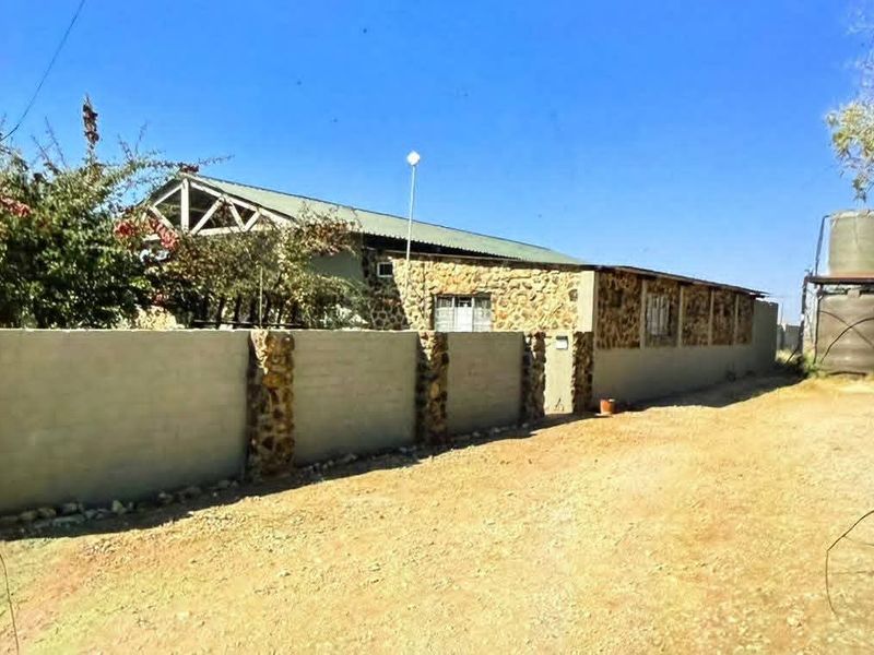 Rear view of the farm property featuring stone-clad exterior walls, a metal roof, and an external water storage tank.