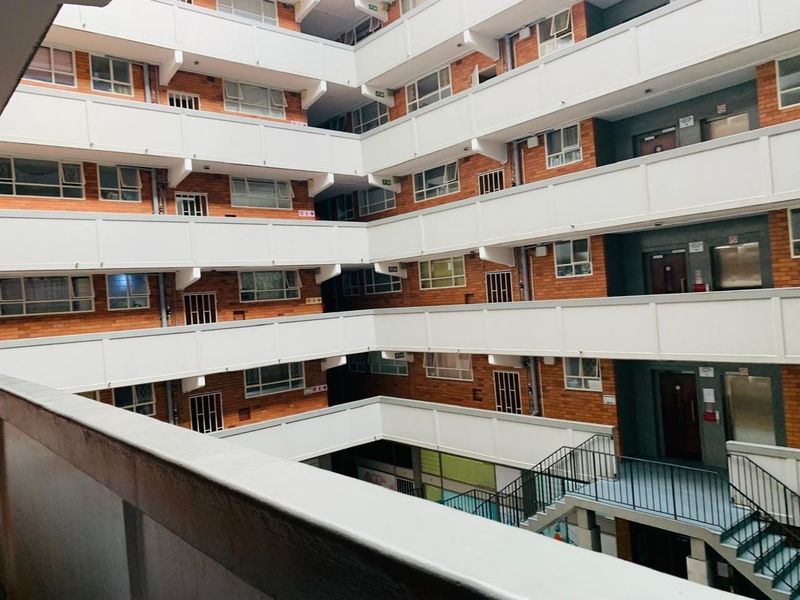 View of the apartment building's central courtyard featuring multi-level balcony walkways, brick facade, and external staircases.
