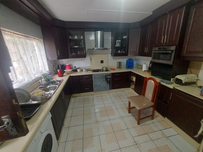 A dated kitchen featuring dark wood cabinetry, built-in appliances, and tiled flooring, offering significant potential for a modern renovation.