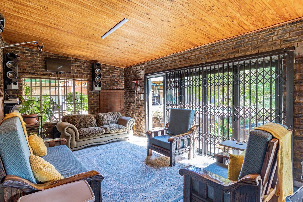 A rustic living area featuring exposed brick walls, a timber-clad ceiling, and security gates leading to the outdoor space.