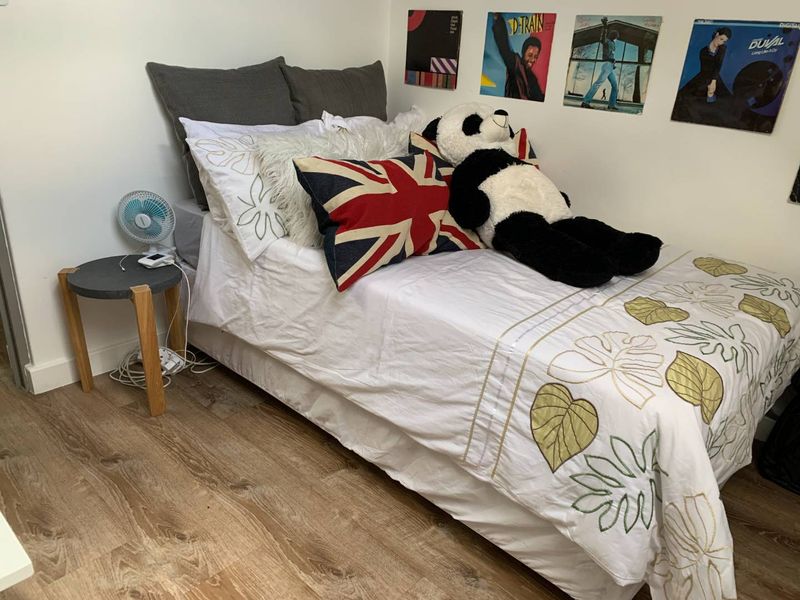 A cozy bedroom featuring durable laminate flooring and neutral wall finishes, providing a comfortable and functional sleeping space.