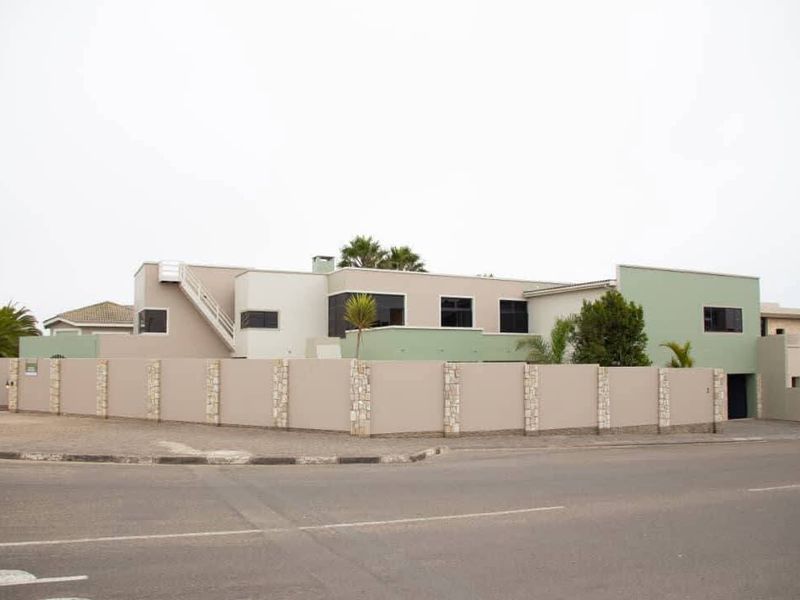 A modern multi-level residential property featuring a secure perimeter wall with stone accents and an external staircase.