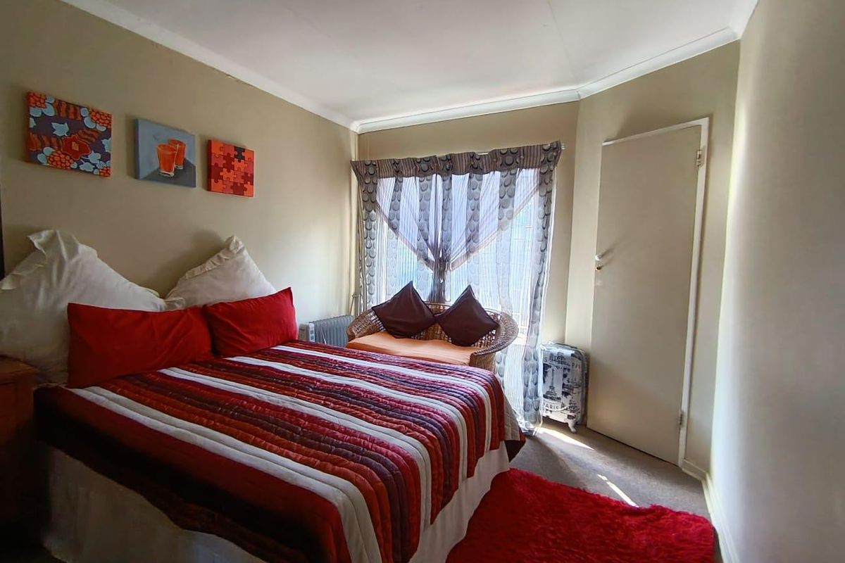 A cozy bedroom featuring neutral wall tones, a built-in cupboard, and a window with natural light.