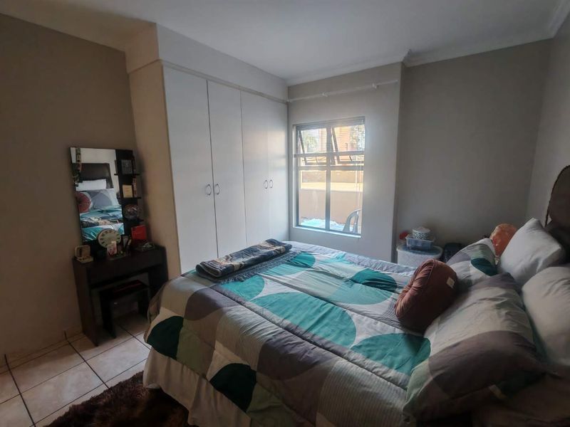 A functional bedroom featuring built-in cupboards, tiled flooring, and a window providing natural light.
