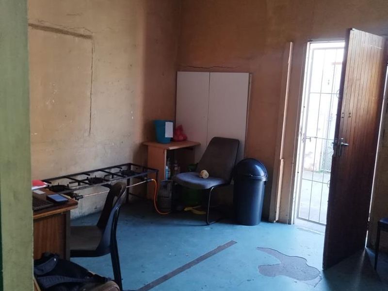 A basic utility room featuring painted concrete flooring and a single exterior door, currently used as a functional workspace.