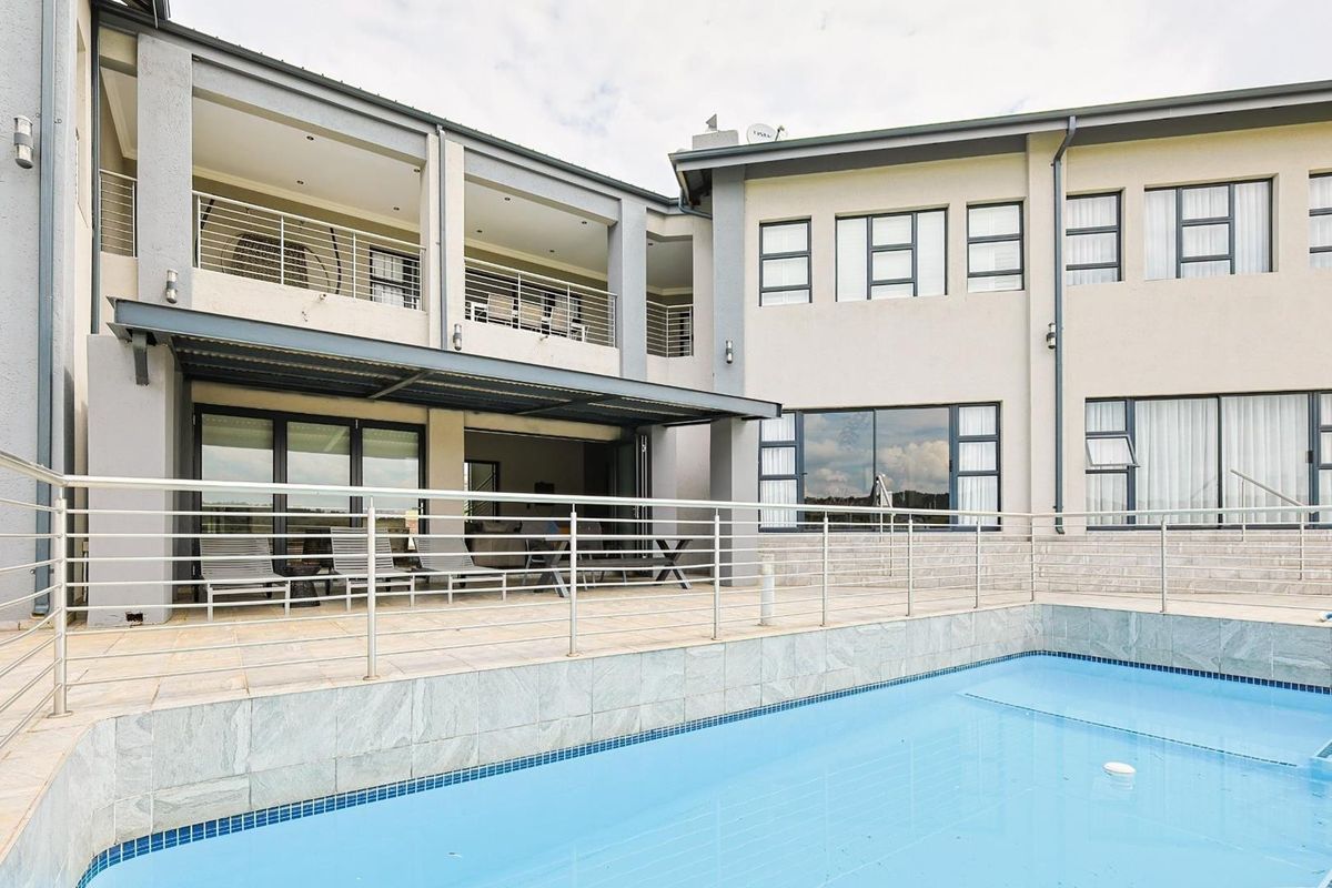 A spacious rear exterior view featuring a swimming pool, a covered patio area, and a multi-level facade with large windows and balconies.