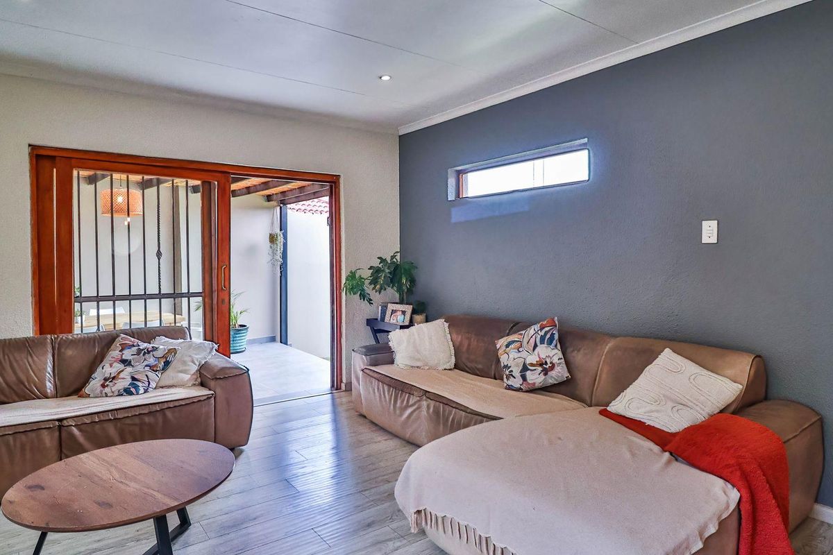 A comfortable living room featuring wood-look flooring, a dark grey accent wall, and a sliding door providing direct access to an outdoor patio area.