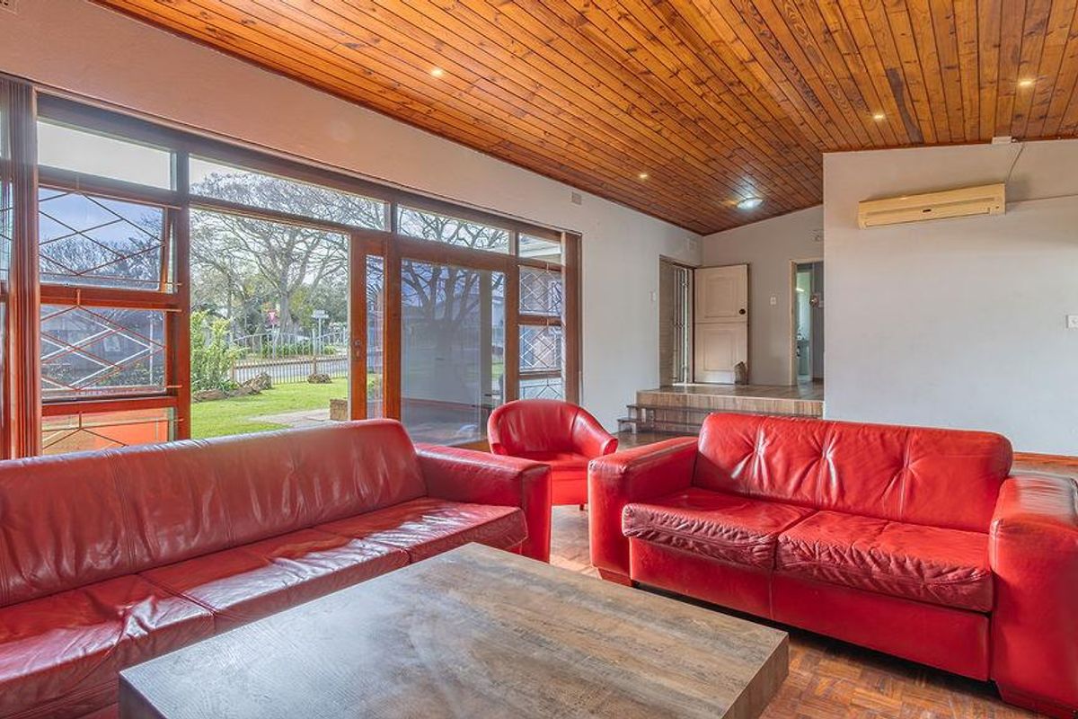 Spacious living room featuring a warm timber-clad ceiling, parquet flooring, and large sliding doors that provide ample natural light and garden access.