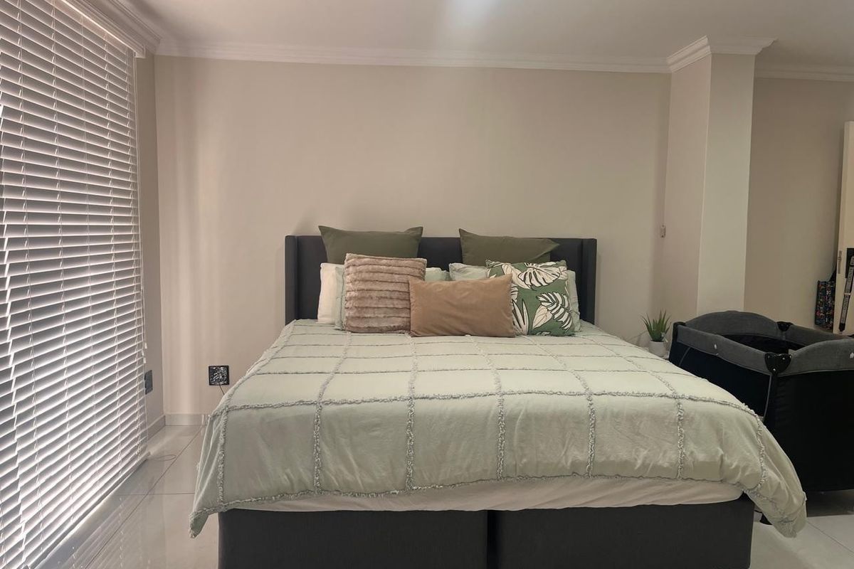 A well-maintained bedroom featuring neutral wall tones, tiled flooring, and venetian blinds, providing a clean and functional living space.