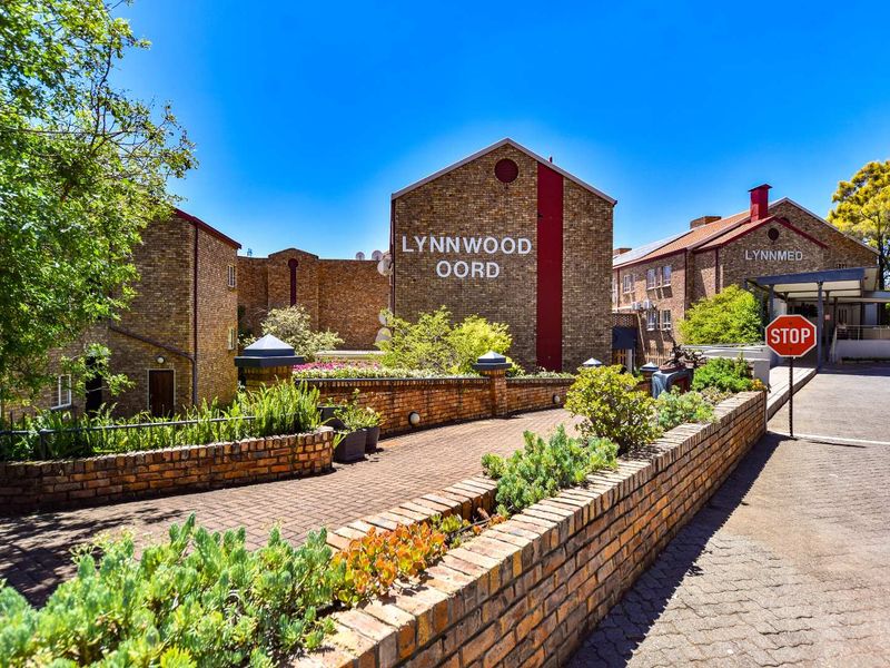 Front entrance view of the Lynnwood Oord retirement village, featuring face brick architecture, paved access roads, and established landscaped garden beds.