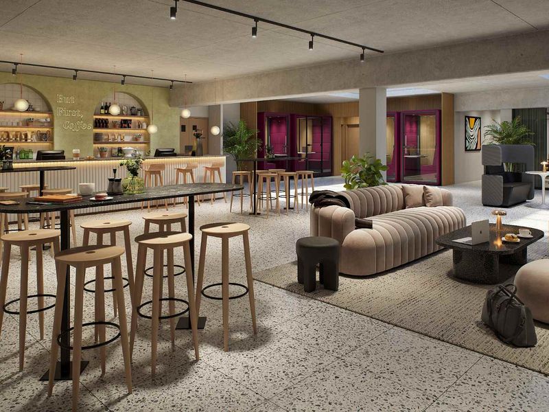 Modern communal clubhouse area featuring a built-in coffee bar, terrazzo flooring, track lighting, and private meeting pods for residents.