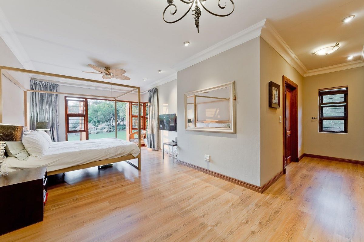 Spacious bedroom featuring warm wood-look flooring, crown molding, recessed lighting, and large glass doors providing direct access to the garden.
