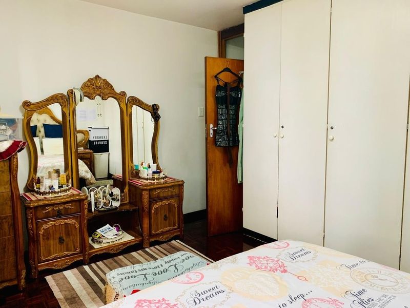 A bedroom featuring wooden flooring and a large built-in wardrobe with white doors.