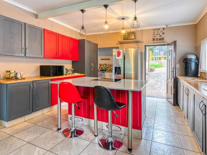 Spacious kitchen featuring a central island with breakfast bar, contrasting cabinetry, stone countertops, and direct access to the rear patio area.