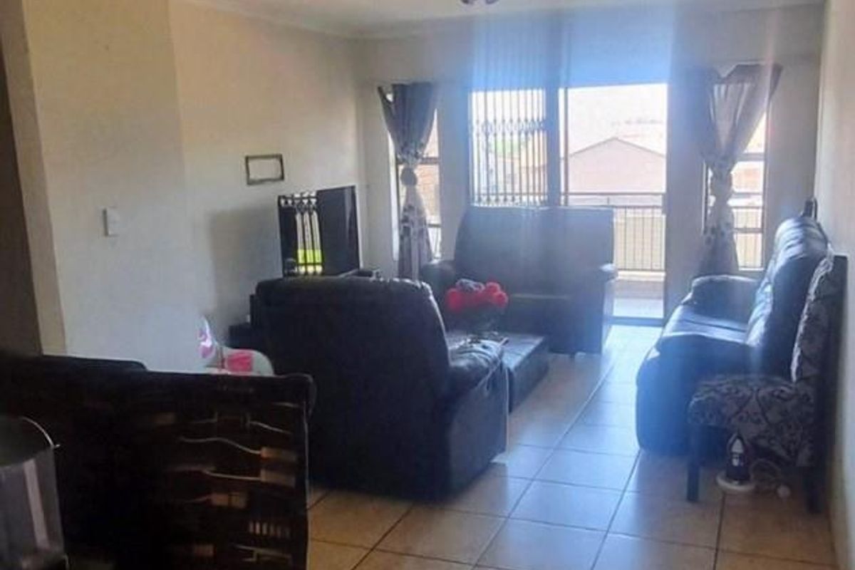 A living room area featuring tiled flooring and a sliding glass door leading to an outdoor space, providing natural light to the interior.