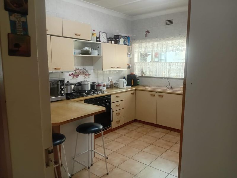 A functional kitchen featuring built-in cabinetry, laminate countertops, a gas cooktop, and tiled flooring, offering a practical layout for daily meal preparation.