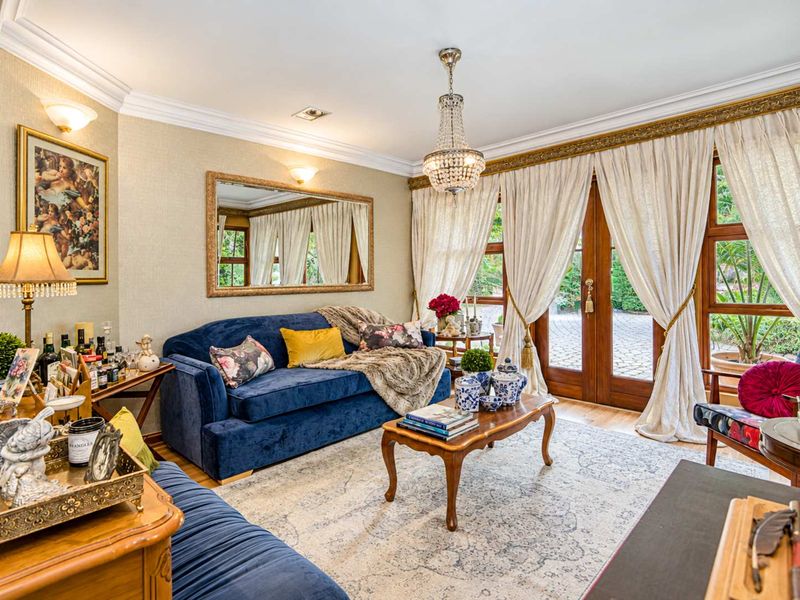 Elegant living room featuring crown molding, a crystal chandelier, and wooden French doors that open to the exterior.