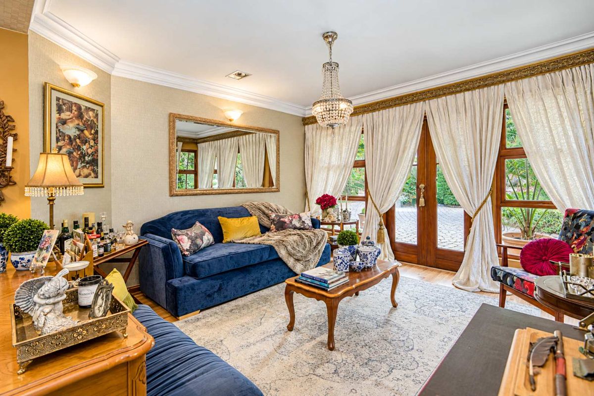 Elegant living room featuring crown molding, a crystal chandelier, and wooden French doors that open to the exterior.