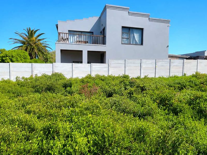 View of the rear elevation of the property featuring a balcony and a precast concrete boundary wall, set against a natural landscape.