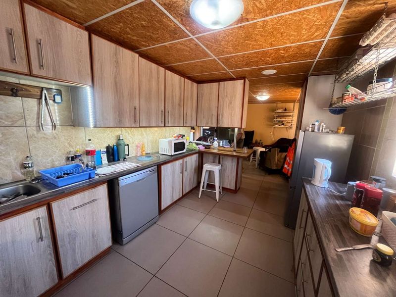 A functional kitchen featuring wood-look cabinetry, tiled flooring, a breakfast bar, and a tiled backsplash, offering a practical layout for daily use.