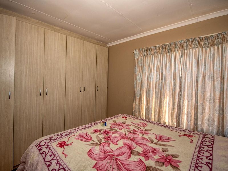 A bedroom featuring light wood-finish built-in cupboards and a coved ceiling, offering a functional space with neutral wall tones.