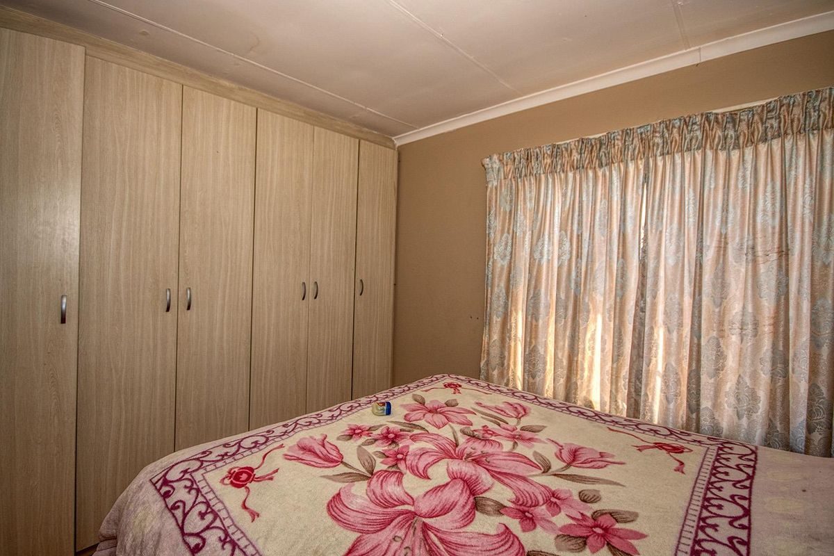 A bedroom featuring light wood-finish built-in cupboards and a coved ceiling, offering a functional space with neutral wall tones.