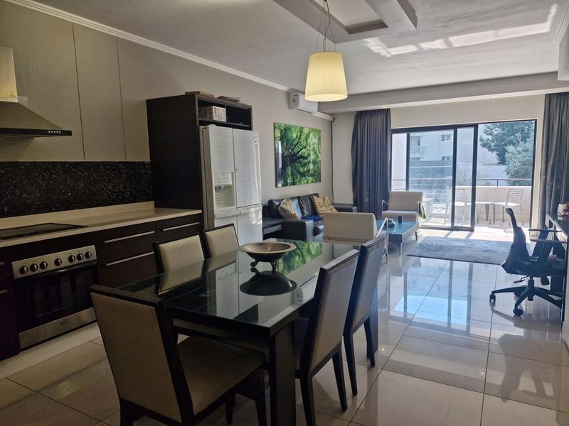 Modern open-plan living area featuring a sleek kitchen with built-in appliances, tiled floors, and large sliding doors leading to a private balcony.