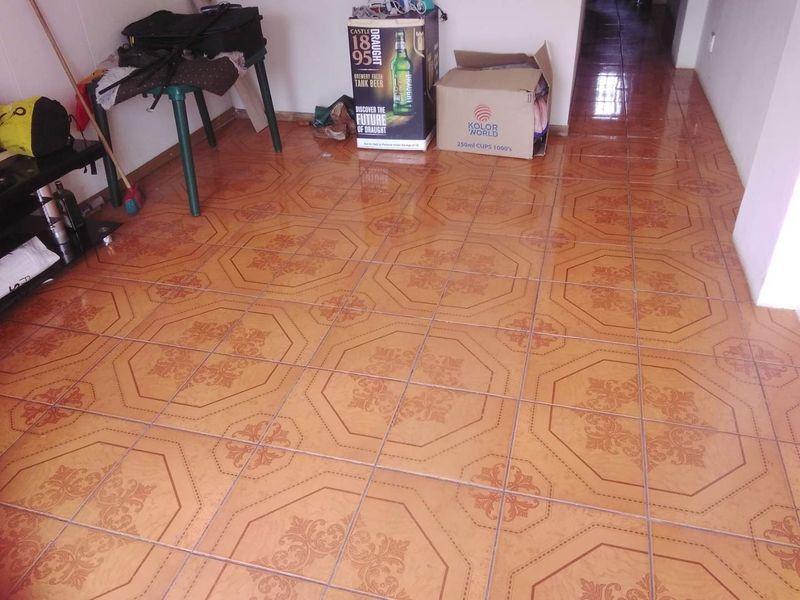 A living area featuring patterned ceramic floor tiles, leading into a hallway space.