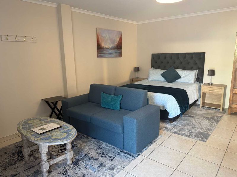 An open-plan studio apartment featuring tiled flooring and neutral wall finishes, combining sleeping and living areas in a functional layout.