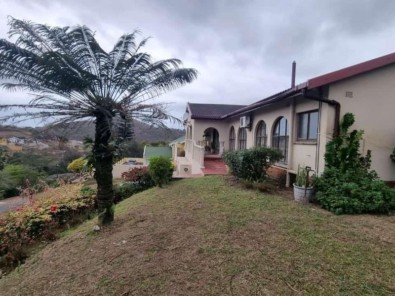 Rear view of the property featuring arched windows, a tiled roof, and a concrete patio area overlooking the surrounding landscape.