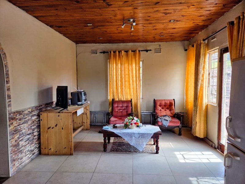 Living room featuring tiled flooring, stone veneer wall accents, and a timber-paneled ceiling with natural light from large windows and a glass door.