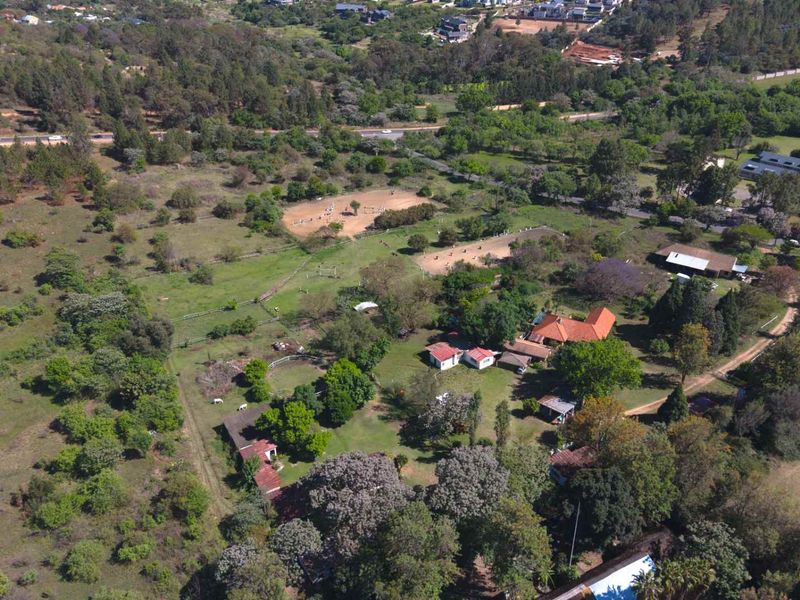 Aerial view of a large farm property featuring multiple outbuildings, equestrian paddocks, and extensive landscaped grounds with mature trees.