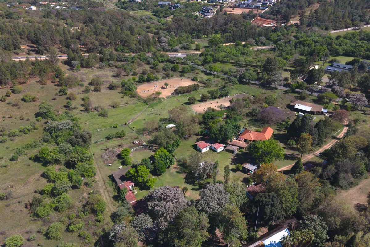 Aerial view of a large farm property featuring multiple outbuildings, equestrian paddocks, and extensive landscaped grounds with mature trees.