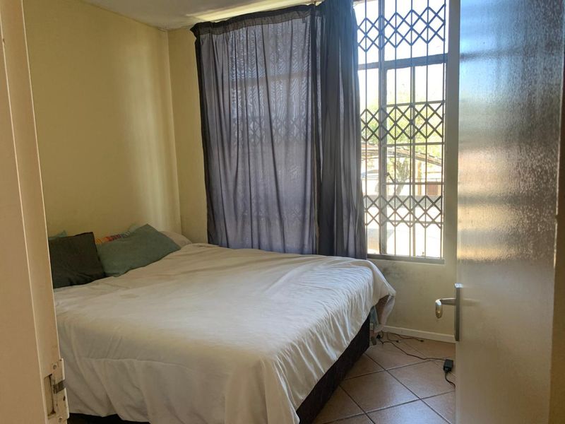 A bedroom featuring tiled flooring and a window fitted with a security gate, requiring cosmetic updates to improve its overall condition.