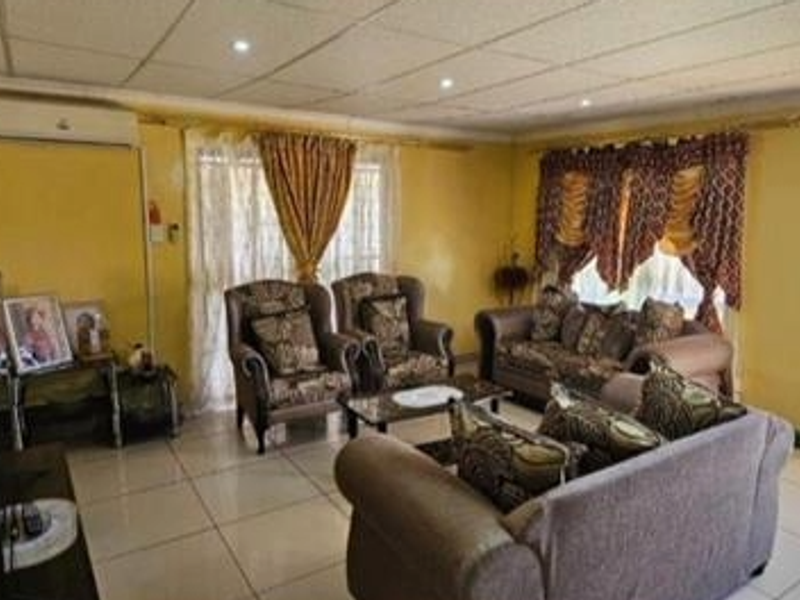 A spacious living room featuring tiled flooring, a split-system air conditioner, and direct access to the outdoor area through a glass panel door.