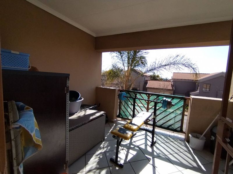 A covered balcony featuring tiled flooring and a metal balustrade, offering an outdoor space suitable for relaxation or utility use.