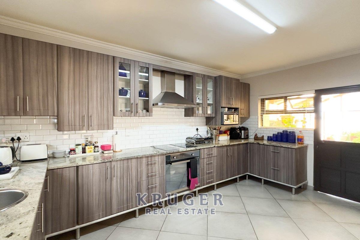 Modern kitchen featuring wood-grain cabinetry, granite countertops, subway tile backsplash, built-in oven, hob, and extractor fan with direct access to the exterior.
