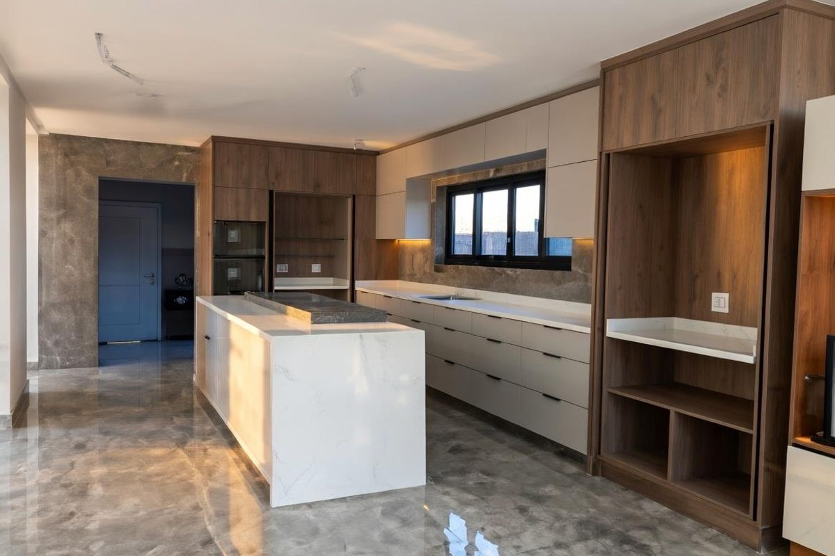 Modern kitchen featuring a large central island with stone countertop, custom cabinetry, integrated appliances, and polished marble-style flooring.