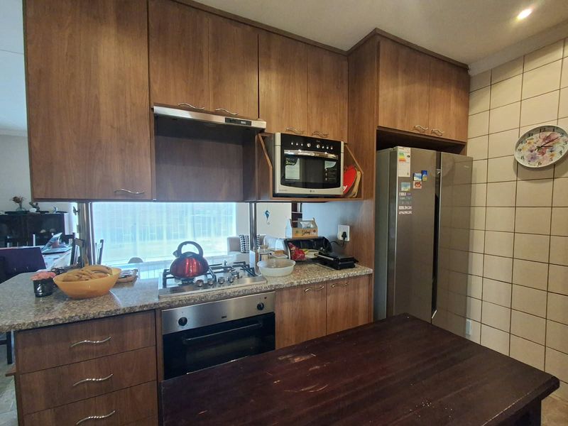 Functional kitchen featuring wood-finish cabinetry, granite countertops, a gas hob, built-in oven, and an integrated extractor fan.