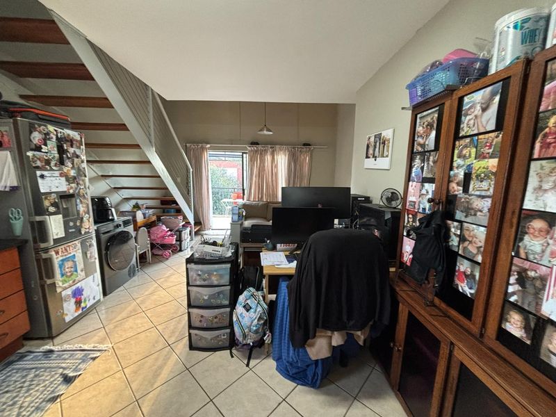 Open plan living area featuring tiled flooring and a staircase, with direct access to an outdoor patio area through a sliding glass door.