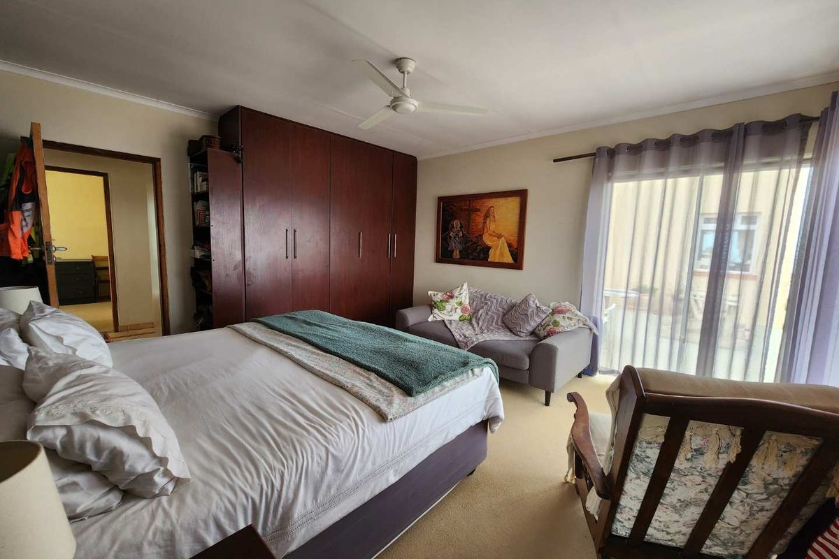 Spacious bedroom featuring built-in wooden cabinetry, a ceiling fan, and sliding glass doors providing access to an outdoor area.
