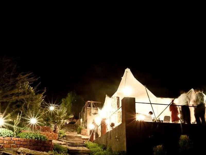 An elevated outdoor deck area at night, featuring stone stairs, brick retaining walls, and integrated lighting, suitable for evening entertainment.
